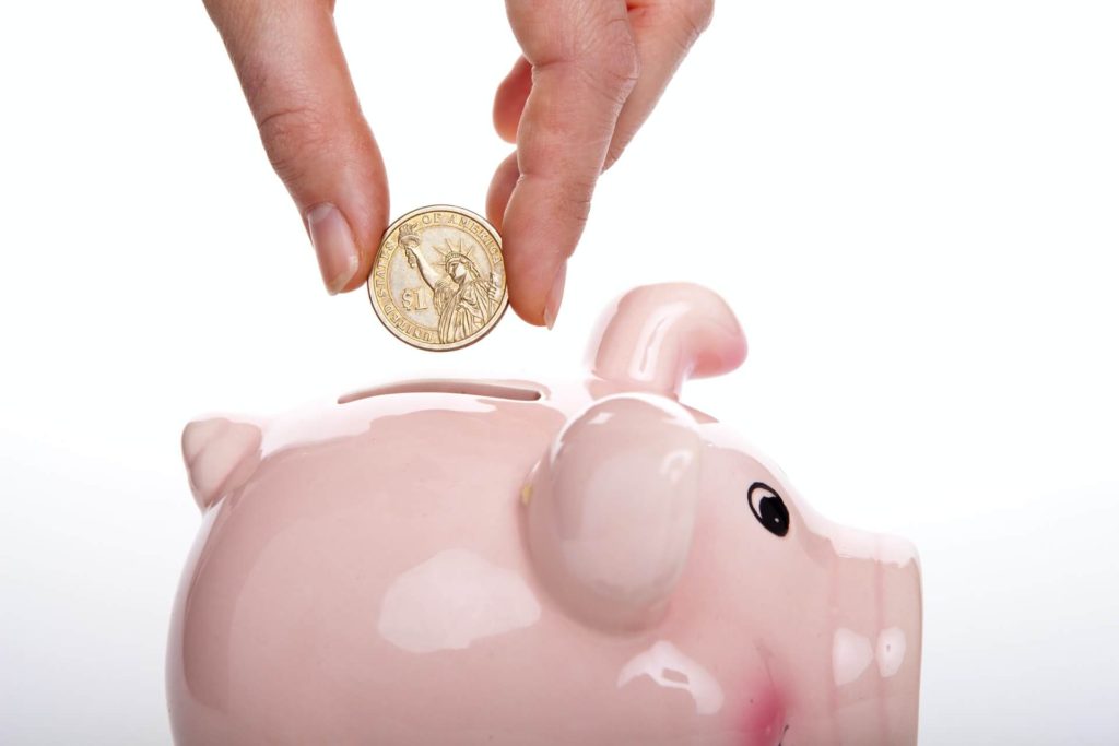 Image of coin being dropped into piggy bank